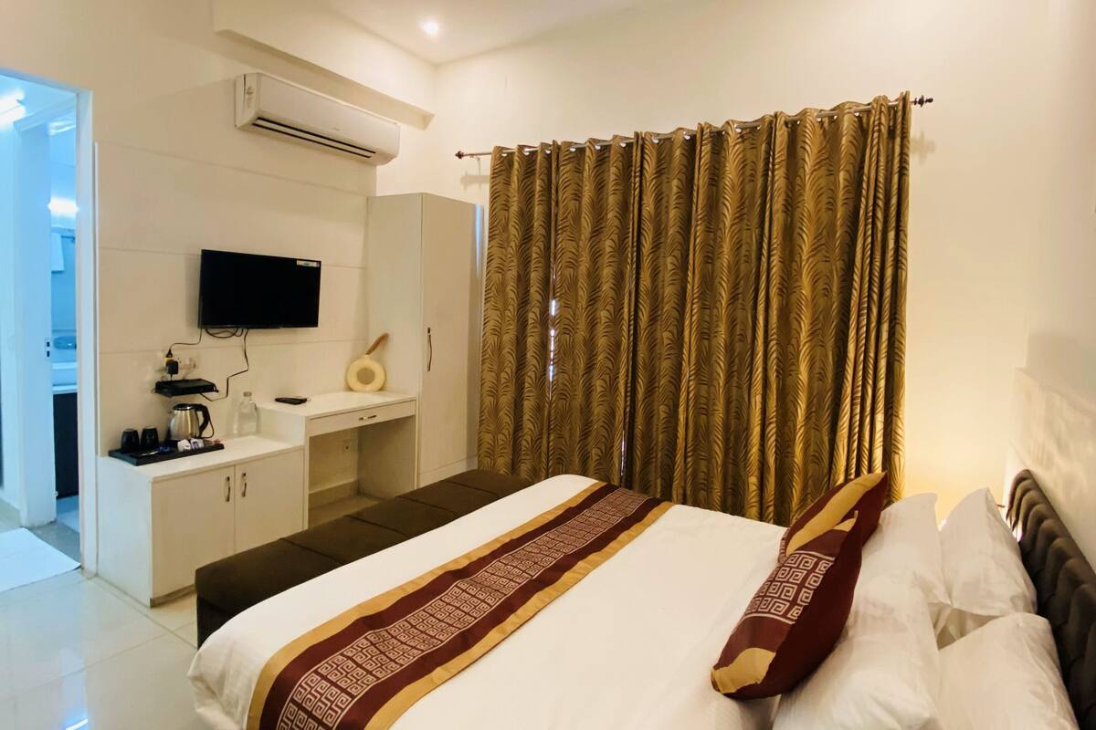 A hotel room with a bed, a TV, a desk, and a ceiling fan.