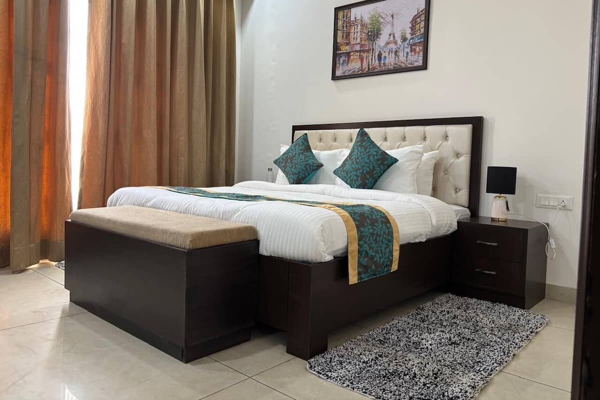 A bedroom with a bed, nightstands, a rug, and a painting on the wall.