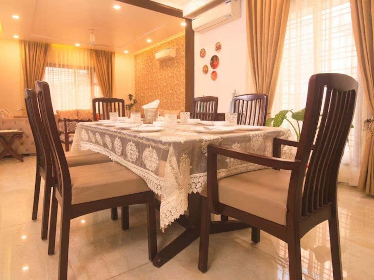 A dining area with a table set for six, surrounded by wooden chairs with cushioned seats.
