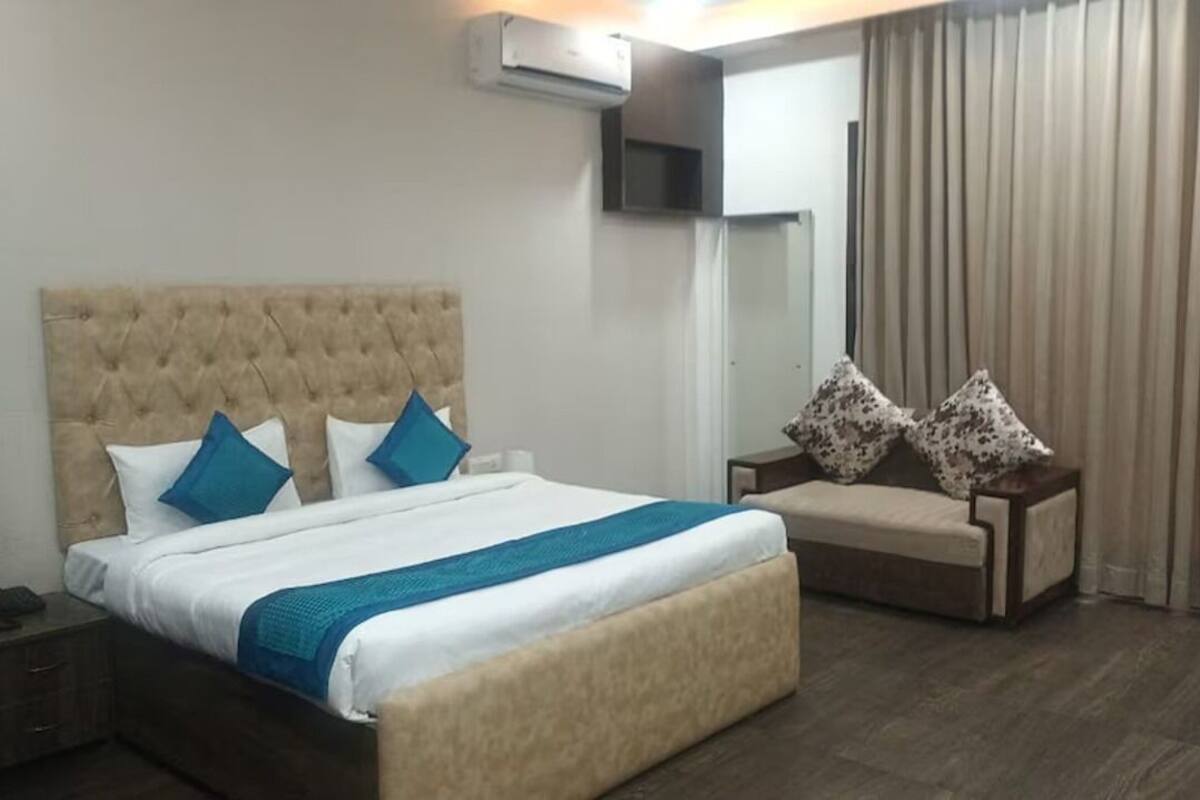 A hotel room with a large bed, a bedside table, a chair, and a window with curtains.