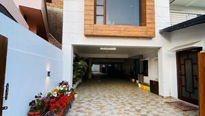 Un edificio moderno con un patio empedrado, plantas en macetas y una puerta de metal.
