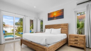 A bedroom with a wooden bed, a nightstand, and a painting of a sunset over water.