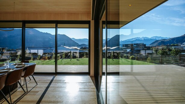 Un comedor moderno con vistas a montañas y a una piscina.