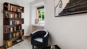 Una habitación con una estantería, un sillón negro y una obra de arte enmarcada en la pared.