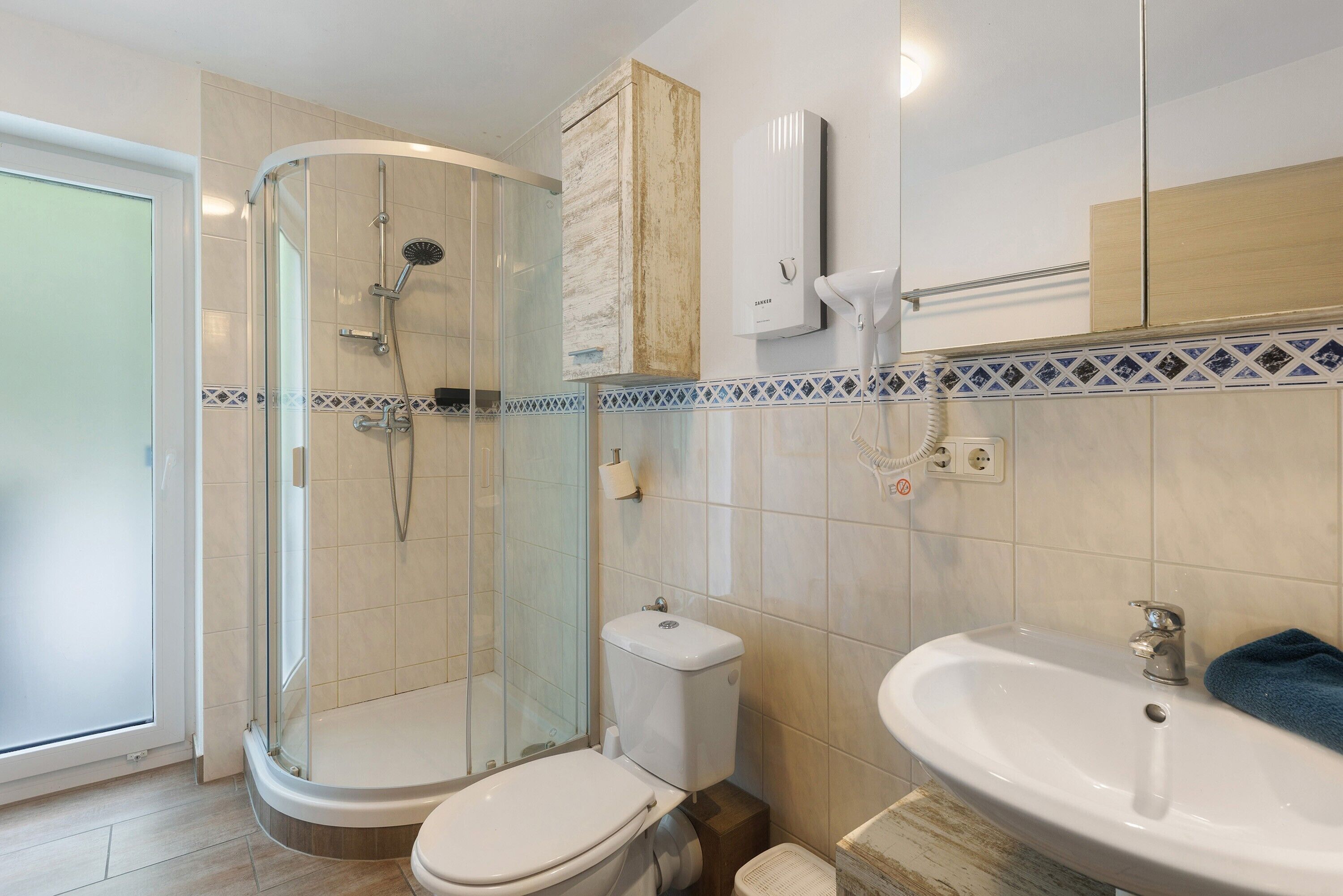 Un baño con ducha de vidrio, inodoro, lavamanos y espejo.