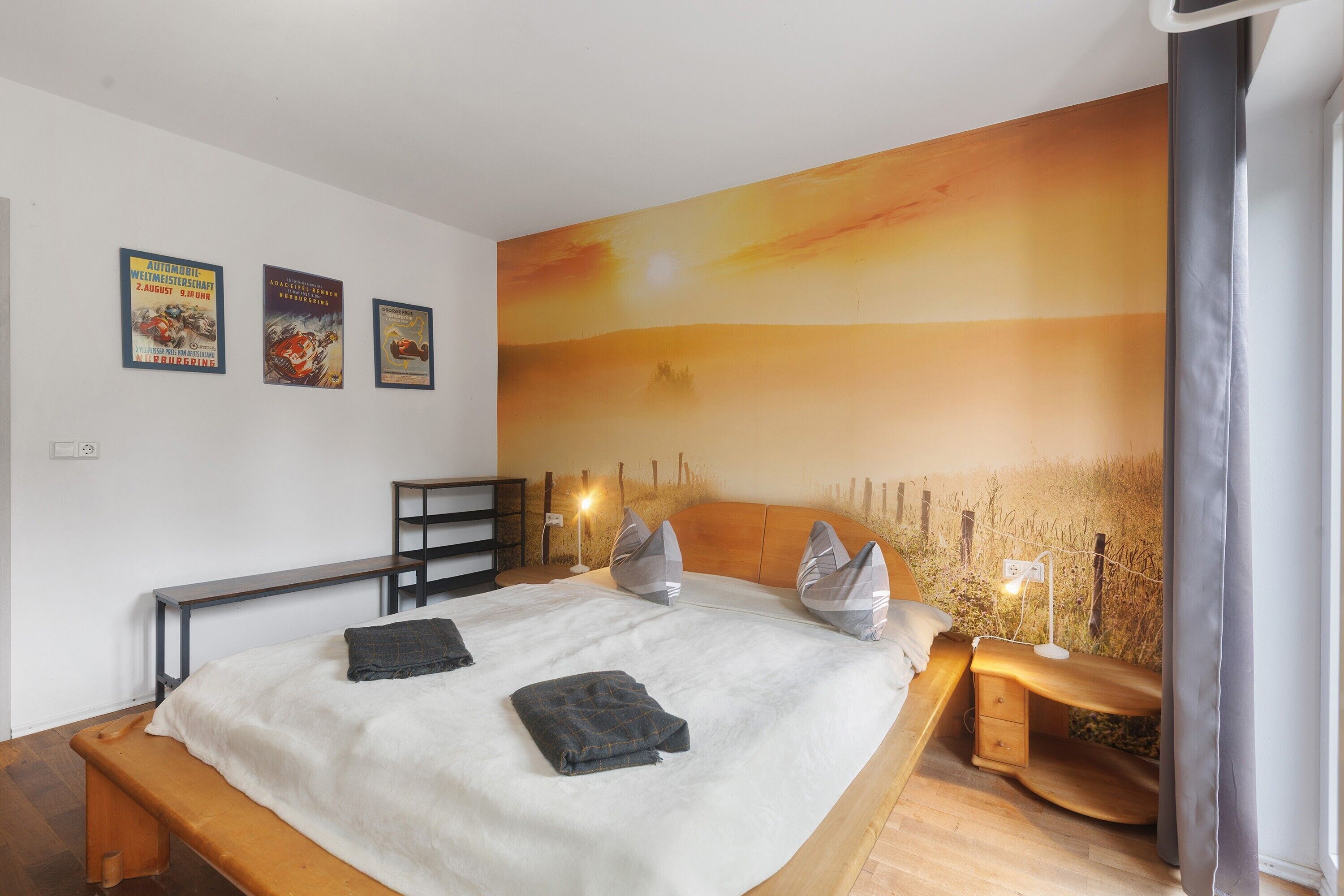 Ein Schlafzimmer mit einem großen Bett, einer Holzbank, einem Nachttisch und einer Wandmalerei.