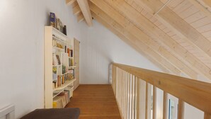 Une pièce avec un plafond en pente, un plancher en bois, une bibliothèque et une fenêtre.