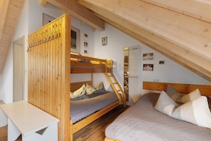 Un lit superposé avec une échelle, un bureau et un lit avec des oreillers.