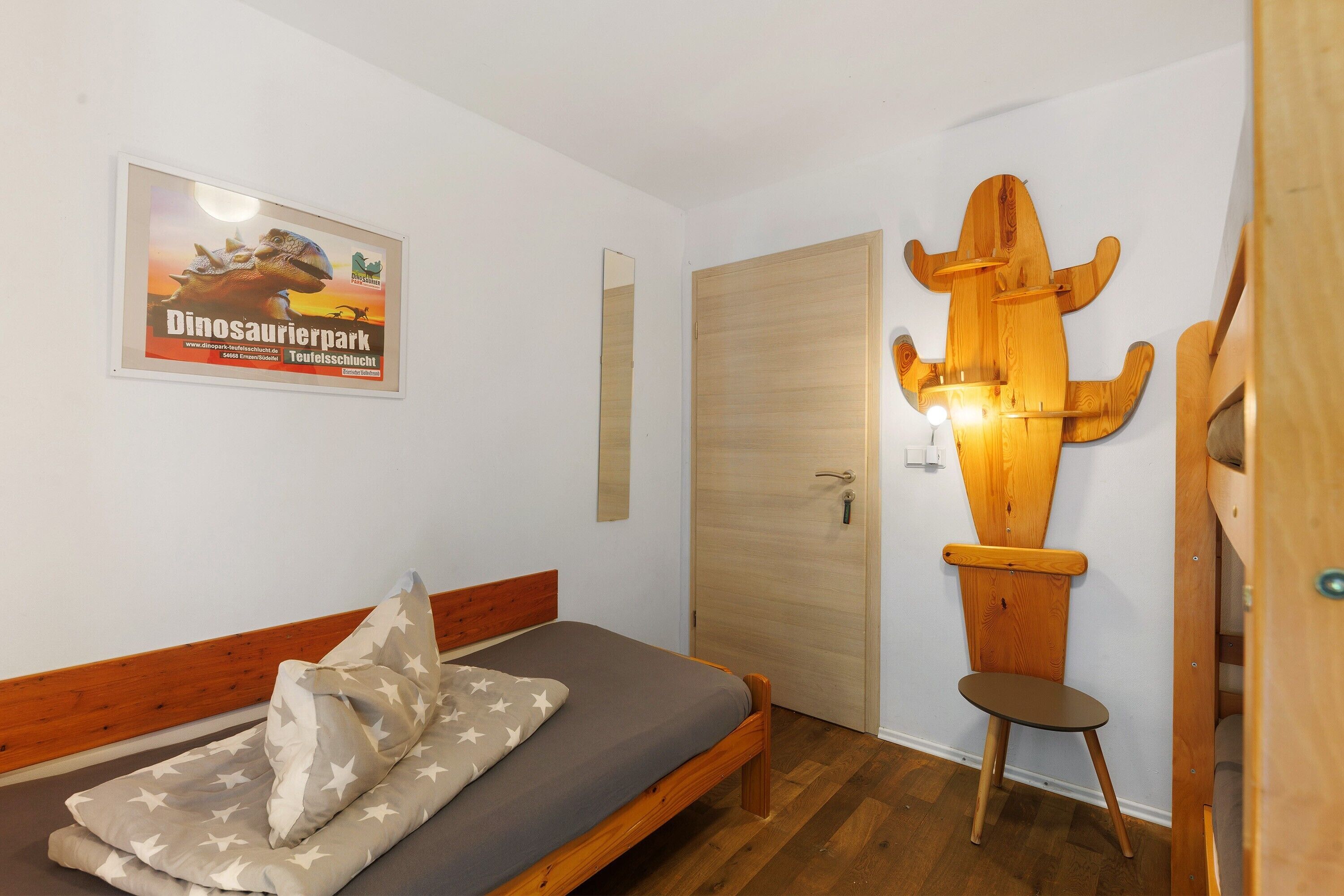 Un dormitorio con cama, un cartel en la pared, una silla de madera y una puerta de madera.