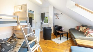 A loft-style room with a bunk bed, a sofa, a small table, and a chair. - Holiday Home 'Enztal' with Shared Terrace (Zweifelscheid)