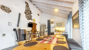 A dining area with a wooden table, chairs, and a kitchen in the background. - Holiday Home 'Enztal' with Shared Terrace (Zweifelscheid)