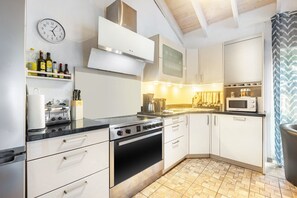A kitchen with a stove, oven, microwave, and various kitchen appliances. - Holiday Home 'Enztal' with Shared Terrace (Zweifelscheid)