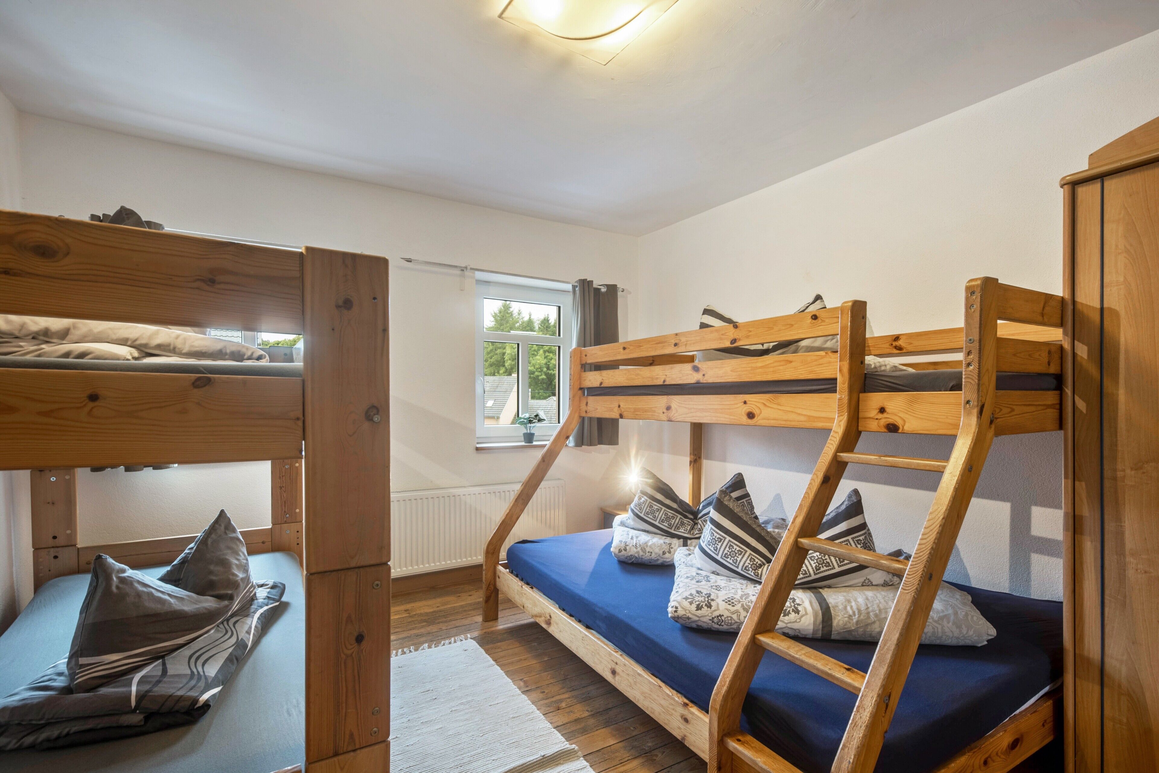 A bunk bed room with a window, wooden walls, and a white ceiling.