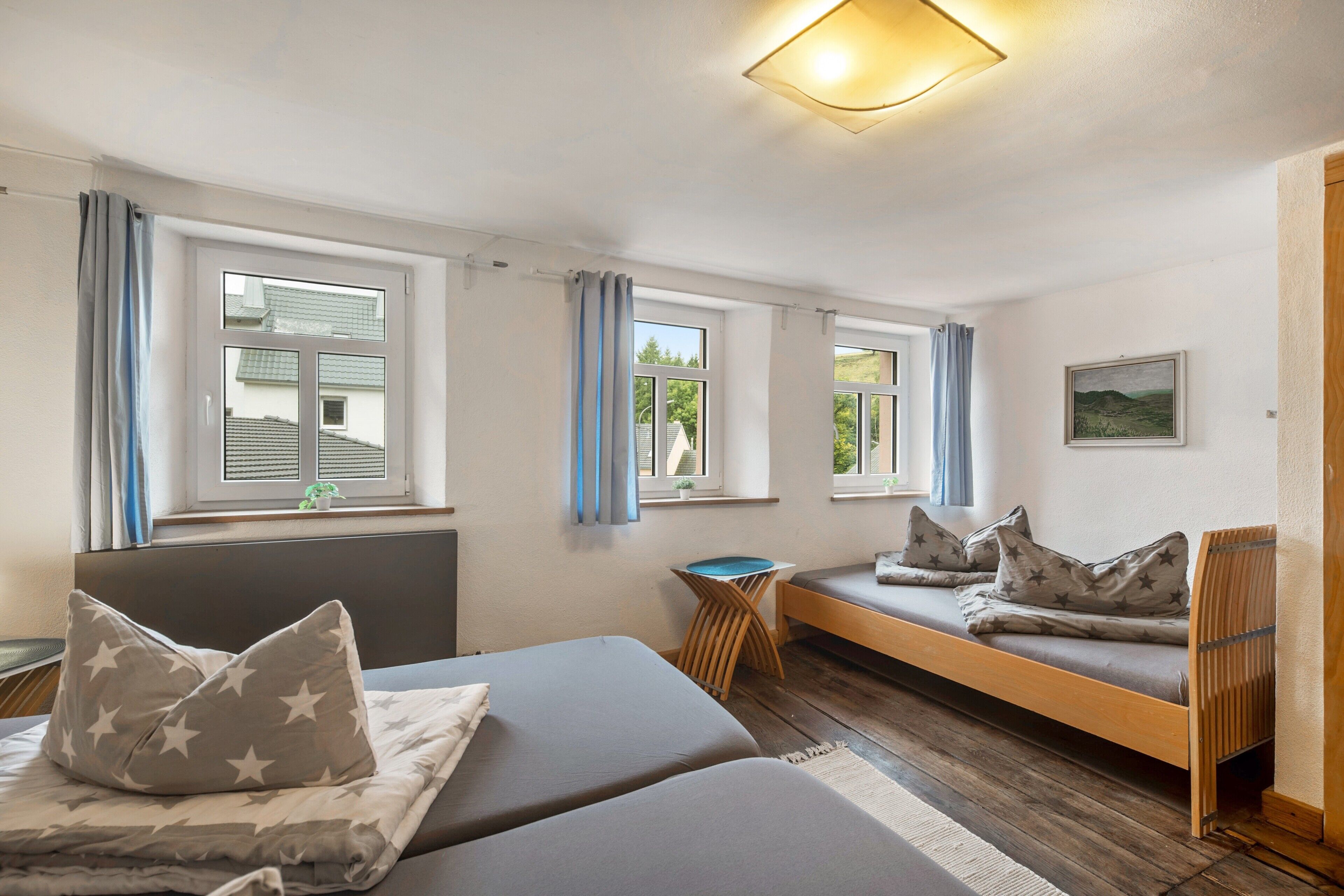 A room with two beds, a small table, and a bench.
