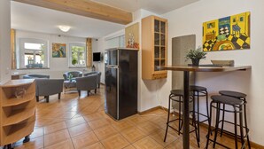 A modern kitchen with a refrigerator, wooden cabinets, and a bar area with stools. - Holiday Home 'Eifellandhaus' with Shared Terrace and Wi-Fi (Zweifelscheid)