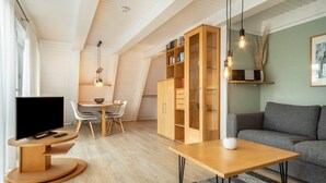 A modern living room with a flat-screen TV, wooden furniture, a bookshelf, and a gray sofa.