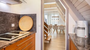 A modern kitchen with a built-in stove, a wooden cutting board, and a coffee maker.