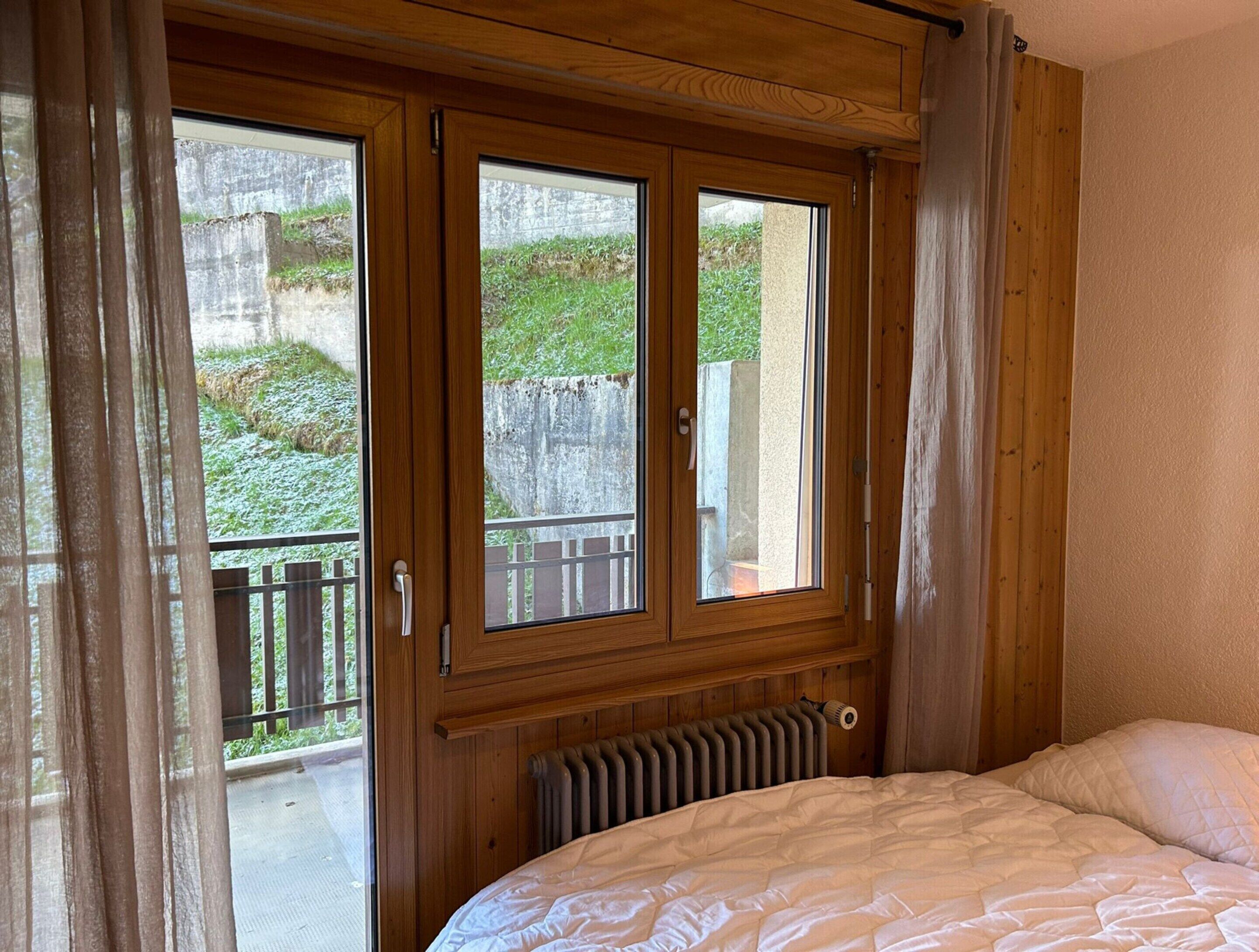 Ein Schlafzimmer mit einem hölzernen Kopfteil, einem Heizkörper und einem Bett mit weißer Bettdecke.