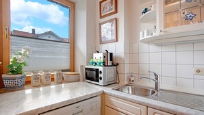 Una cocina con lavavajillas Bosch, microondas, fregadero y ventana con vistas a una casa.