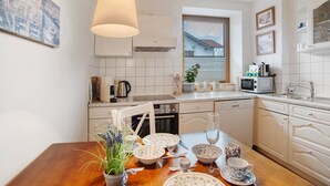 Una cocina con armarios blancos, una mesa de comedor de madera y una lámpara colgante.