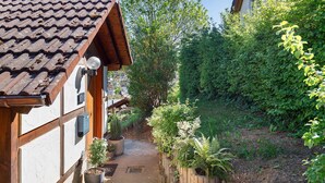 Un sendero estrecho bordeado por edificios de madera con tejados de baldosas, rodeado de exuberante vegetación y plantas en macetas.