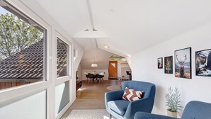 Una sala de estar moderna con ventanas amplias, una zona de comedor y obras de arte en las paredes.