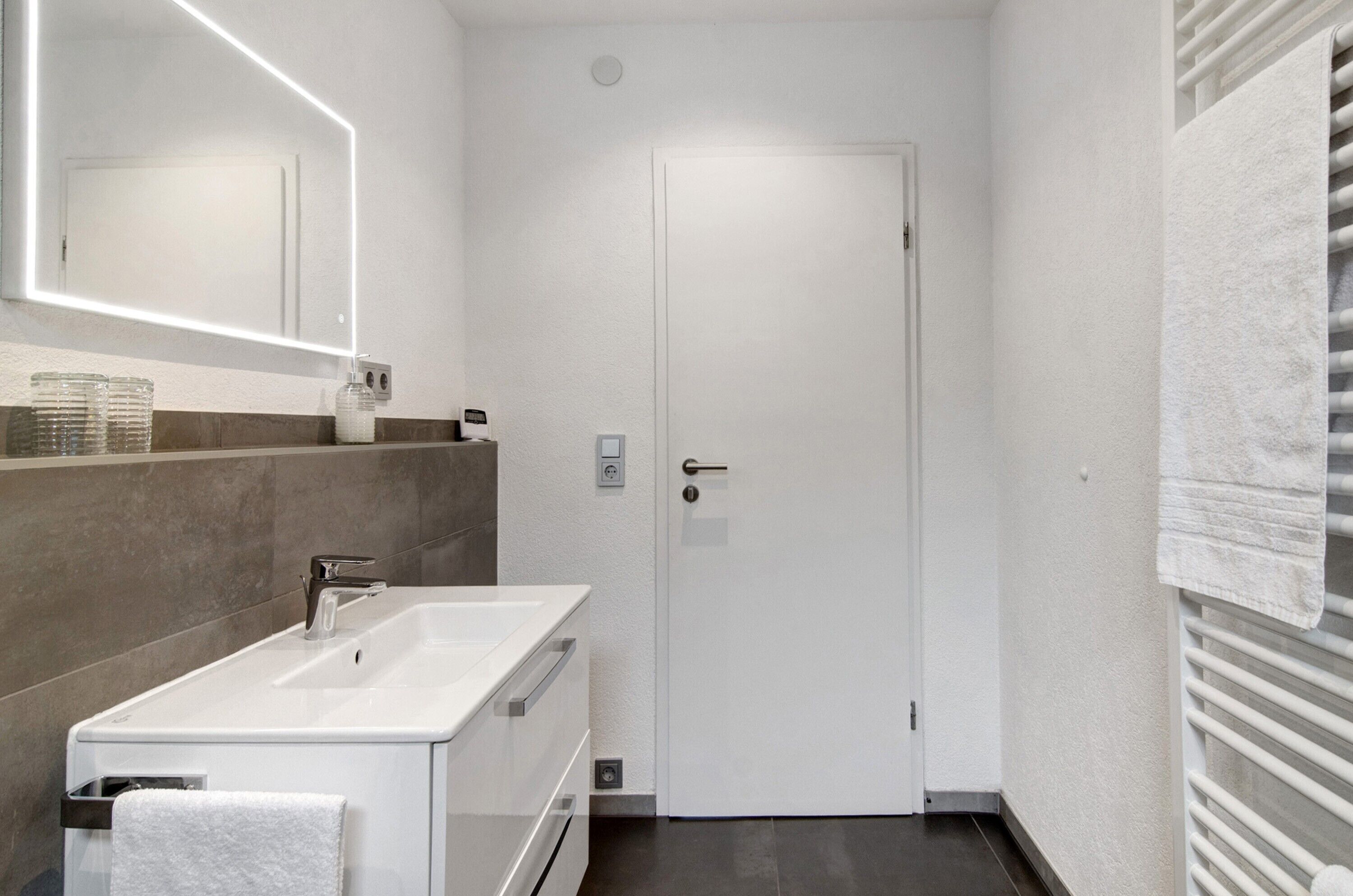 Ein modernes Badezimmer mit Waschbecken, Spiegel und Handtuchhalter.