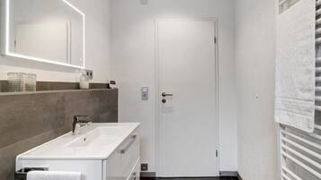 Ein modernes Badezimmer mit Waschbecken, Spiegel und Handtuchhalter.