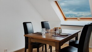 A dining area with a wooden table, black chairs, and a view of the sky through a skylight.