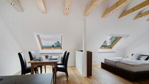 A modern interior with a dining area, a sofa bed, and skylights.