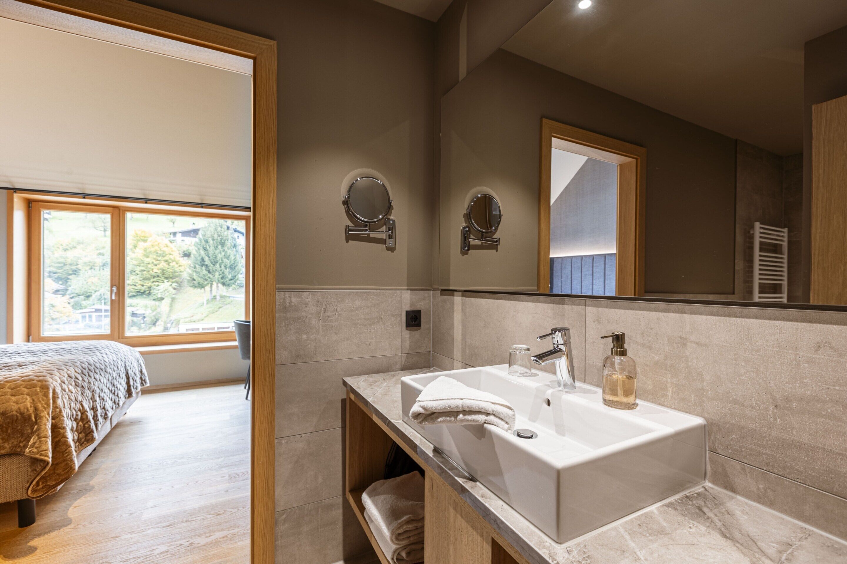 A modern bathroom with a large sink, two mirrors, and a towel rack.