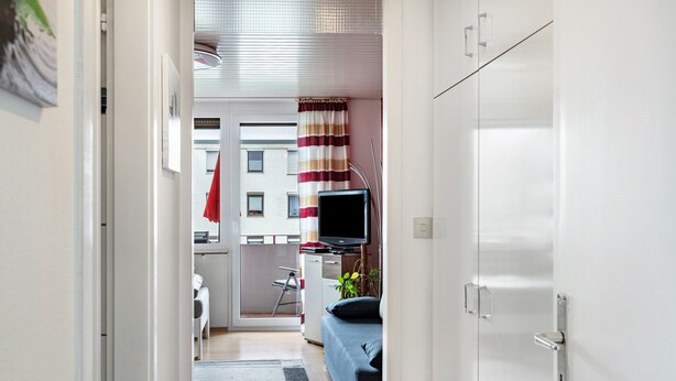 Habitación de hotel moderna con cama, televisión, escritorio y vistas al exterior.