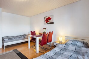A bedroom with a bed, a small table with chairs, a nightstand, and a wall-mounted picture.