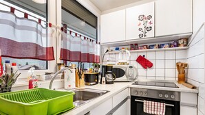 Una cocina moderna con armarios blancos, un escurreplatos verde, una cafetera y un microondas.