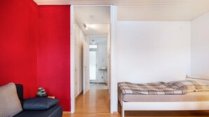 Una habitación con una cama, un sofá y una pared roja.