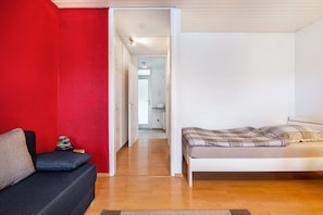 A room with a bed, a sofa, and a red wall. - Apartment 'Szafranzimmervermietung' with Balcony and Wi-Fi (Winnenden)