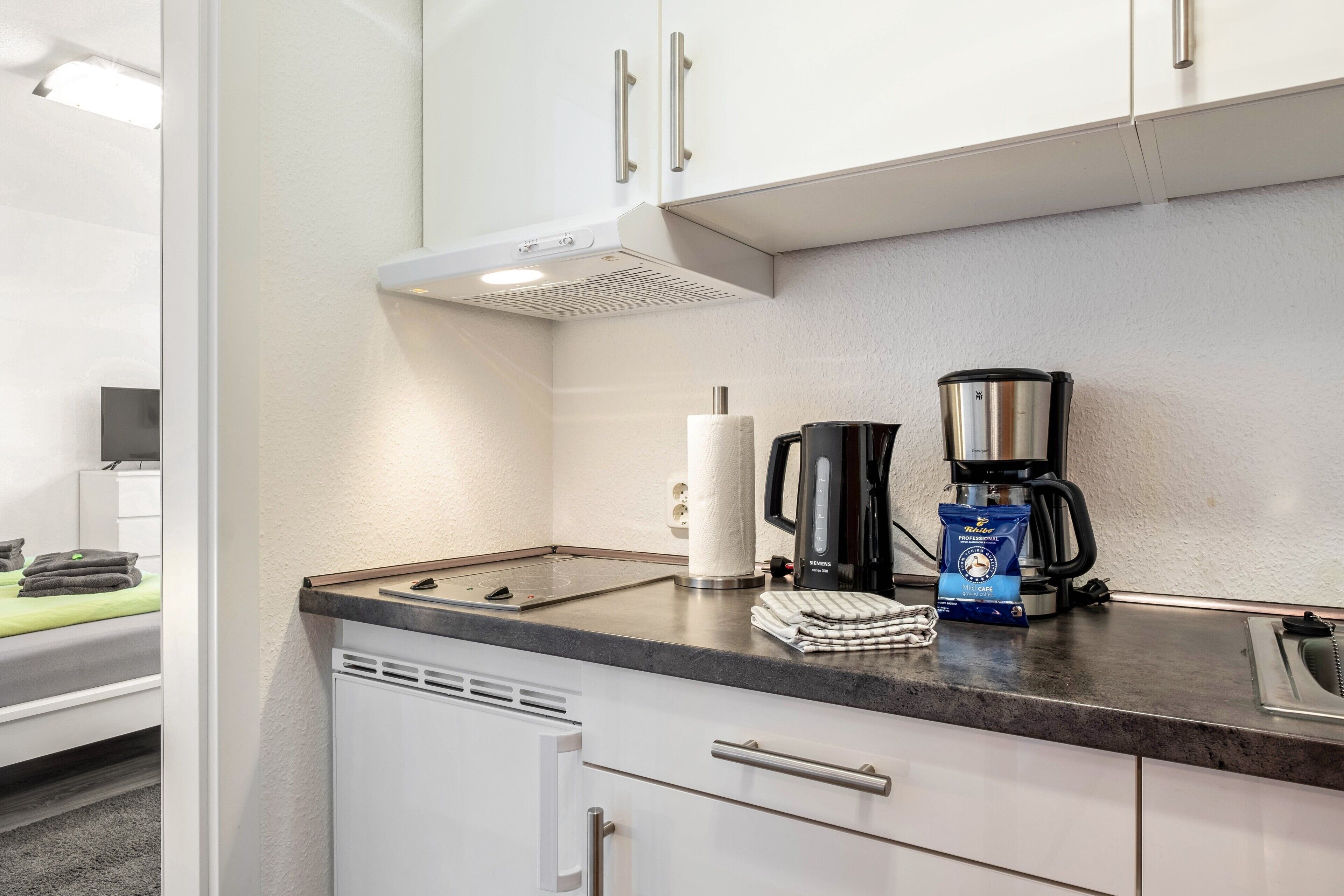 Eine Küchenzeile mit Kaffeemaschine, Wasserkocher und einer Kaffeepackung.
