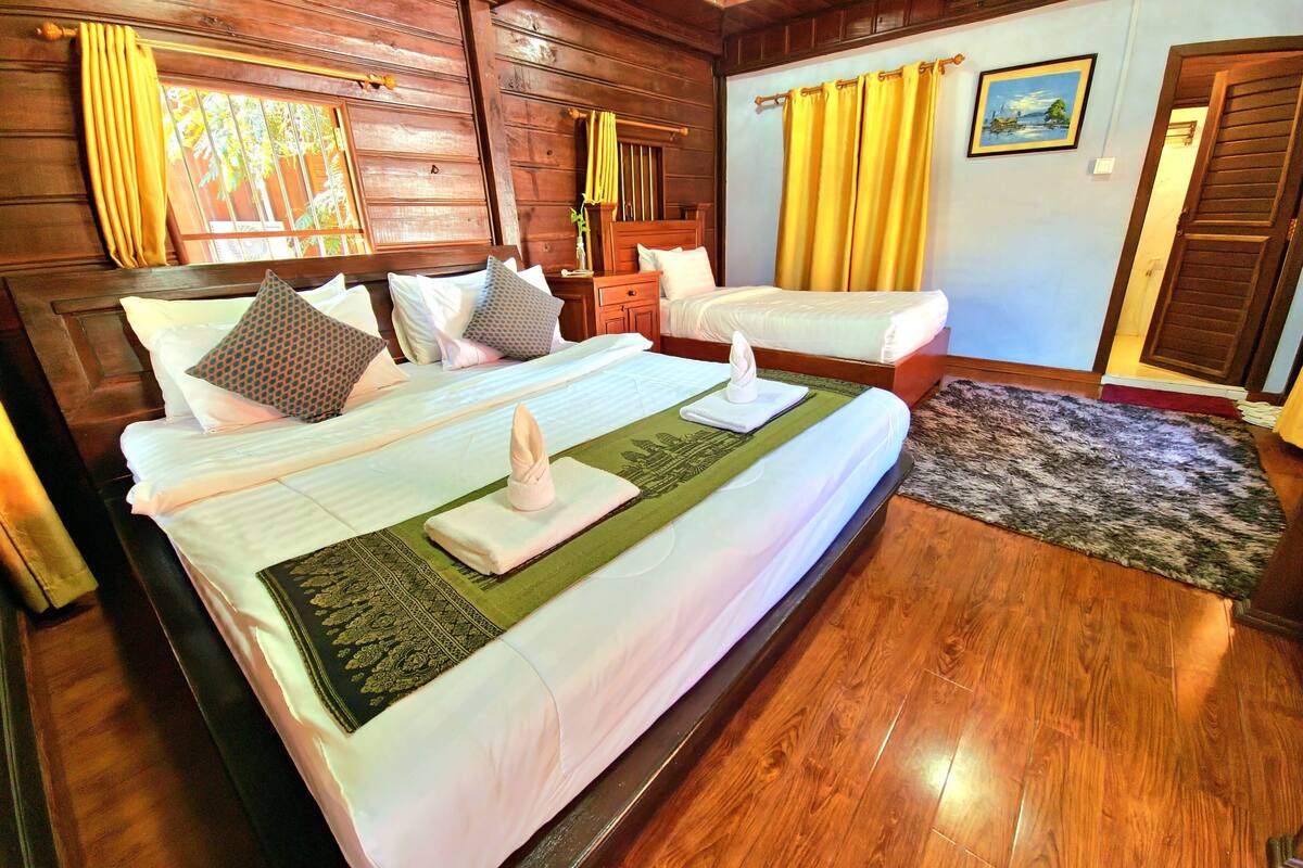 A wooden-paneled bedroom with a large bed, a smaller bed, and a desk.