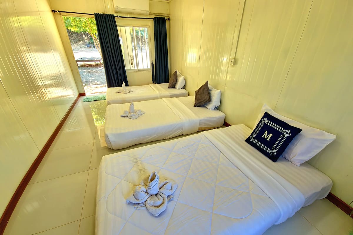 A hotel room with two beds, each with a towel and pillow.