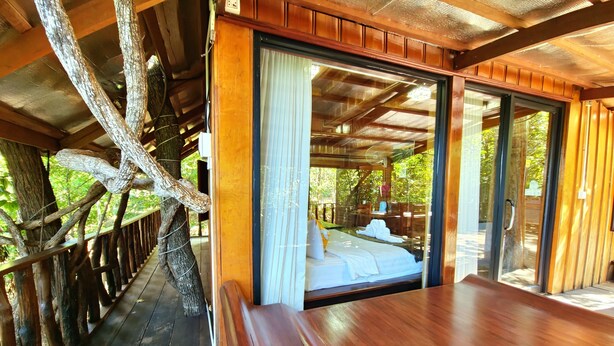 Une cabane en bois avec un lit, un banc et une vue sur l’extérieur.