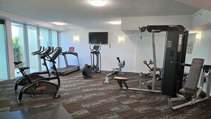 Un gimnasio con cintas de correr, elípticas y equipo de pesas.