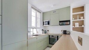 Une cuisine moderne avec des meubles de couleur vert clair, un four à micro-ondes, un four traditionnel et un évier.