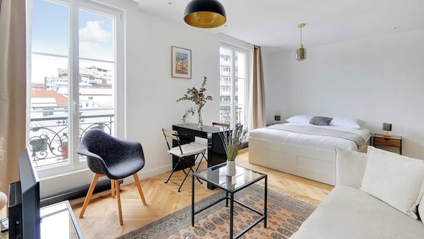 Une chambre moderne avec un lit, un bureau, une chaise et une grande fenêtre.