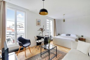 Un dormitorio moderno con una cama, un escritorio, una silla y un ventanal grande.