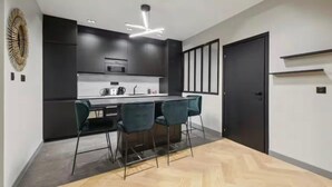 Una cocina moderna con una isla central, taburetes de bar e iluminación colgante.