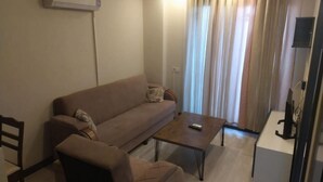 A living room with a sofa, armchair, coffee table, and a TV stand. - pozcu forum plus (Mersin)