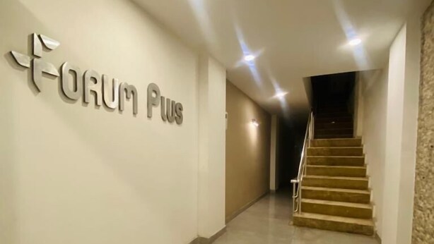 A hallway with a sign reading "Forum Plus" on the wall, leading to a staircase. - pozcu forum plus (Mersin)