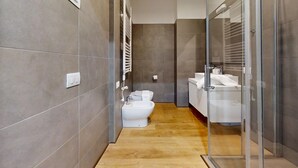 A modern bathroom with a toilet, bidet, and glass-enclosed shower area.