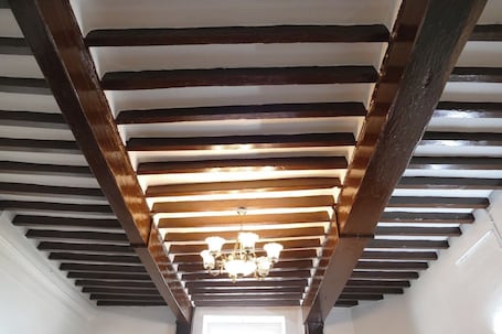 A staircase with exposed wooden beams and a chandelier.