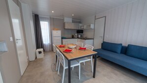 A compact living space with a dining table set for four, a blue sofa, and a kitchenette in the background. - Normandie Veules-les-roses, Terraced House (Veules-les-Roses)